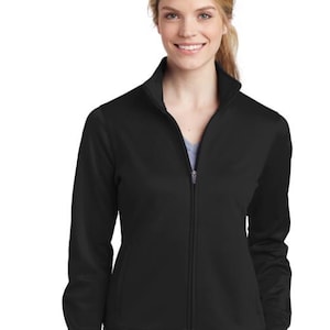 Puede incluir: Una chaqueta negra con cremallera y cuello alto. La chaqueta tiene un tejido liso y ligeramente texturizado.