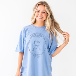 girl wearing a washed denim comfort colors t-shirt with custom grow in grace floral frame printed design