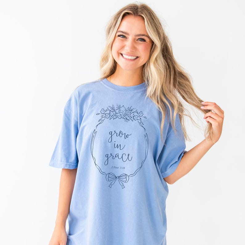 girl wearing a washed denim comfort colors t-shirt with custom grow in grace floral frame printed design