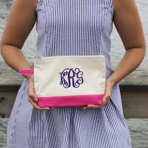 Pode incluir: Uma bolsa de lona branca com z&iacute;per, com fundo rosa e um monograma roxo "KRG" bordado na frente.