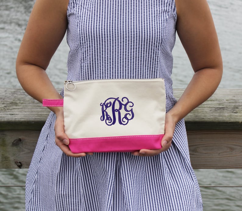 Pode incluir: Uma bolsa de lona branca com z&iacute;per, com fundo rosa e um monograma roxo "KRG" bordado na frente.