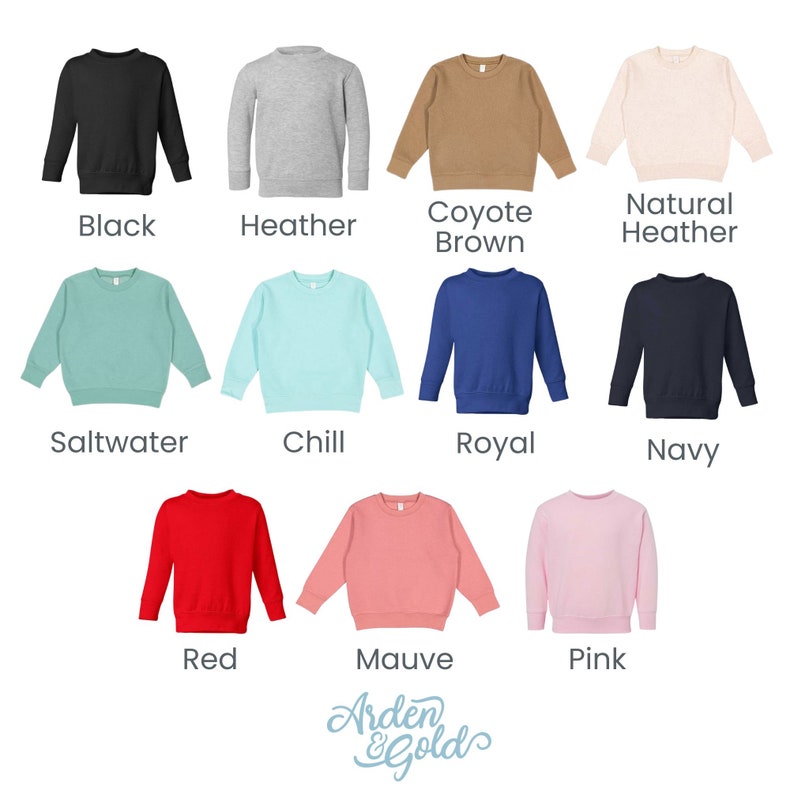 K&ouml;nnte beinhalten: Eine Auswahl von 12 Sweatshirts in verschiedenen Farben f&uuml;r Kleinkinder, darunter Schwarz, Heather Grey, Coyote Braun, Natur Heather, Salzwasser, Chill, Royalblau, Marine, Rot, Mauve und Pink. Die Sweatshirts sind in einem Raster auf wei&szlig;em Hintergrund angeordnet.