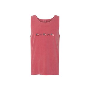 A crimson comfort colors tank top with embroidered mini usa flags and dainty bow design across the chest in an alternating pattern