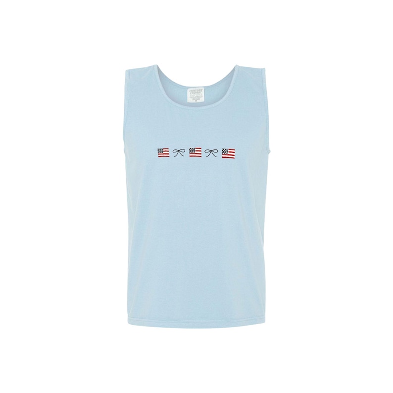 A chambray comfort colors tank top with embroidered mini usa flags and dainty bow design across the chest in an alternating pattern