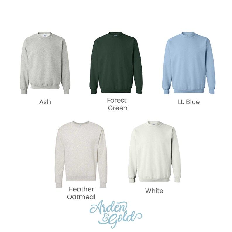 May include: Five crewneck sweatshirts in different colors: ash, forest green, light blue, heather oatmeal, and white. The sweatshirts are laid out on a white background.