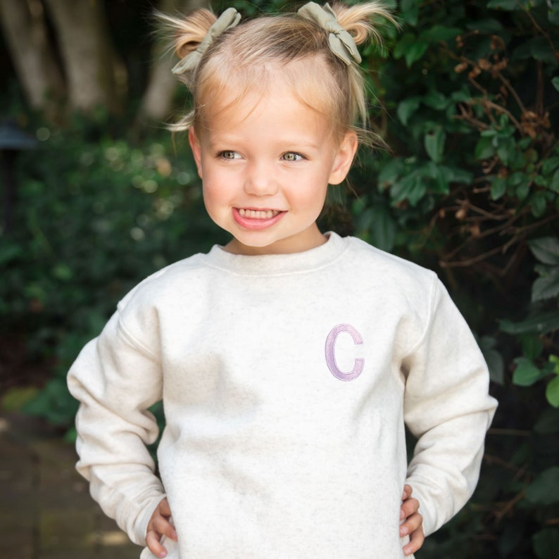 little girl wearing a custom single initial embroidered on the left chest