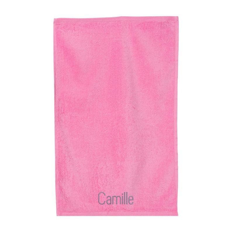 Puede incluir: Una toalla de mano rosa con el nombre "Camille" bordado en hilo plateado.