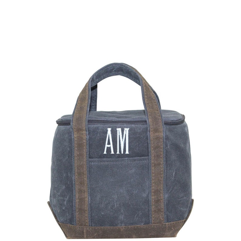 May include: A gray canvas lunch bag with brown leather trim and a zipper closure. The bag has two top handles and the initials "AM" embroidered on the front.