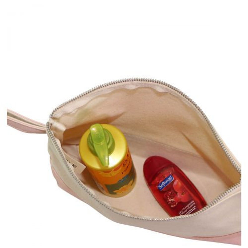 Pode incluir: Uma bolsa de viagem com z&iacute;per rosa e bege com um puxador de z&iacute;per. A bolsa est&aacute; aberta e cont&eacute;m uma garrafa amarela de protetor solar e uma garrafa vermelha de sabonete l&iacute;quido. A garrafa de sabonete l&iacute;quido tem o texto "Softsoap" impresso.