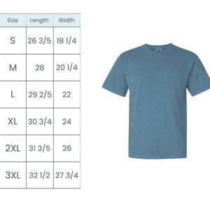 May include: A solid blue-green short-sleeved t-shirt. A size chart is to the left, with measurements in inches for sizes S through 3XL. The shirt has a crew neck and a relaxed fit, suitable for casual wear.