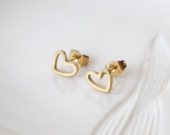 Puede incluir: Un par de pendientes de botón de corazón de color dorado. Los pendientes están hechos de acero inoxidable y tienen un diseño simple y minimalista.