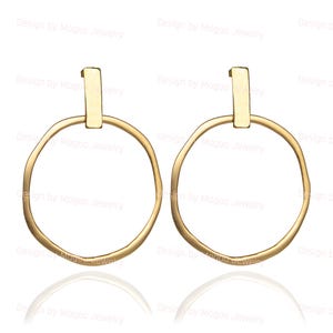 May include: A pair of gold-toned hoop earrings with a textured, hammered finish. The hoops are circular and have a slightly irregular shape. The earrings have a simple, minimalist design.