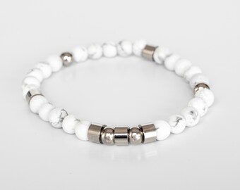 May include: White marble bead bracelet with silver-colored metal accents. The bracelet features round, marbled beads and cylindrical metal spacers. The design is simple and elegant, suitable for everyday wear.