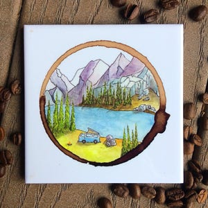 May include: A watercolor painting of a mountain landscape with a blue van parked in front of a lake. The painting is framed by a coffee ring.