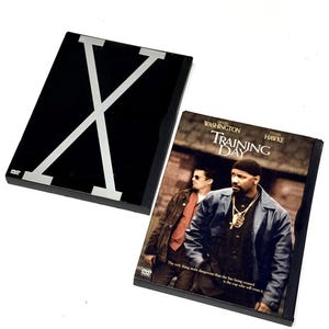 May include: Two DVD cases. One is black with a silver "X" design. The other is a DVD case for the movie "Training Day" starring Denzel Washington and Ethan Hawke. The case has a brown and black cover.