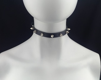 Op de afbeelding: Een zwarte leren choker met zilveren piramidevormige studs.