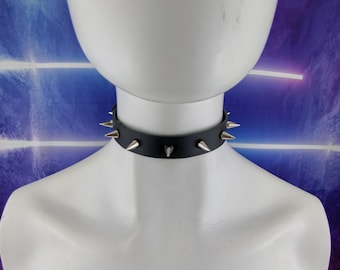 Op de afbeelding: Een zwarte leren choker met zilveren spikes. De choker is op een wit mannequin.