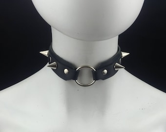 May include: A black leather choker with silver spikes and a silver ring.