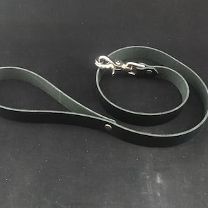 May include: A black leather dog lead with a silver clip. The lead is approximately 1.2 metres long.
