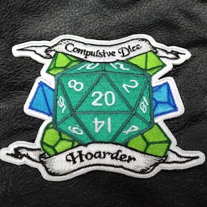 May include: Embroidered patch featuring a large teal twenty-sided die, surrounded by green and blue dice shapes. The patch reads "Compulsive Dice Hoarder" in white script on banners. The patch is on a black leather-like surface.