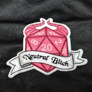 May include: Pink and white embroidered patch with a 20-sided die with devil horns and the text "Neutral Bitch".