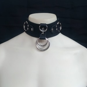 May include: Black leather choker with silver metal rings and hardware.