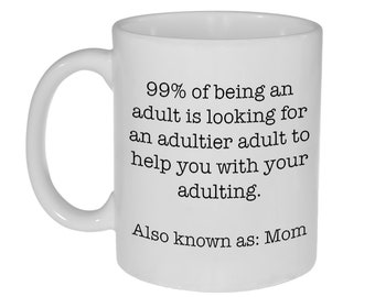 May include: White ceramic coffee mug with black text that reads "99% of being an adult is looking for an adultier adult to help you with your adulting. Also known as: Mom"