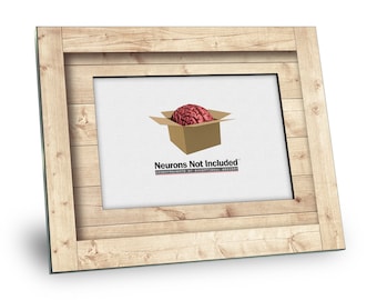 May include: A wooden picture frame with a white background. The image inside the frame shows a brain inside a cardboard box with the text "Neurons Not Included" and the tagline "Instruments of Exceptional Mystery".