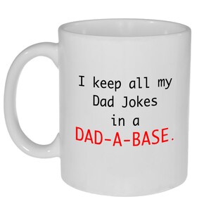 May include: White ceramic coffee mug with a black and red design. The mug reads "I keep all my Dad Jokes in a DAD-A-BASE."