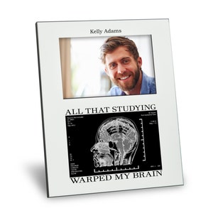 May include: White picture frame with a black and white image of a brain scan and the text "All that studying warped my brain". The frame has a photo of a man smiling in the top section.