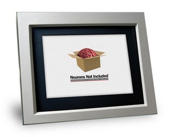May include: A silver picture frame with a black mat and a white background. The image shows a brain inside a cardboard box with the text "Neurons Not Included" and "Accoutrements of Exceptional Greenery".