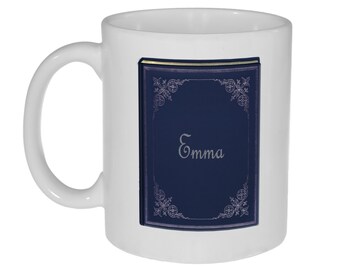 May include: White ceramic mug with a blue book design. The book has a gold border and the name "Emma" is written in silver lettering.