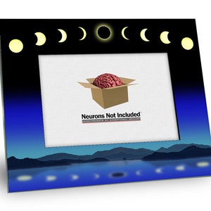 May include: A black picture frame with a blue and white night sky scene. The frame has a cutout of the phases of the moon and a black circle in the center. The text "Neurons Not Included" is printed on the frame.