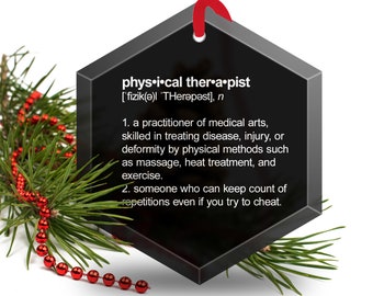 May include: Black hexagonal ornament with a white definition of "physical therapist" and a phonetic pronunciation. The ornament has a red string attached to the top.