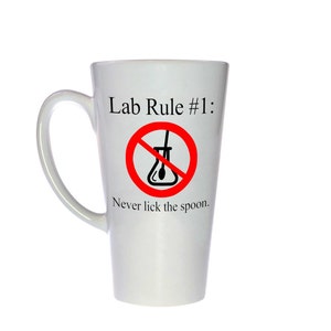 May include: White ceramic latte mug with a red circle and a diagonal line through a beaker. The text reads "Lab Rule #1: Never lick the spoon."