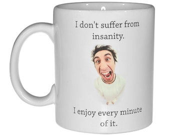 May include: White ceramic mug with a black and white image of a man with a surprised expression. The mug has the text "I don't suffer from insanity. I enjoy every minute of it." printed on it.