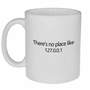 May include: White ceramic mug with black text that reads "There's no place like 127.0.0.1"