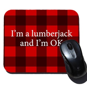May include: Red and black checkered mouse pad with the text "I'm a lumberjack and I'm OK". A black computer mouse is on the mouse pad.