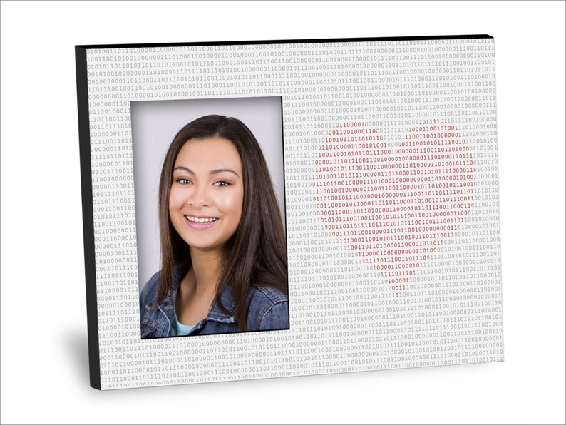 May include: A black picture frame with a white background and a red heart shape made of binary code. The frame has a photo of a young woman with long brown hair smiling at the camera.