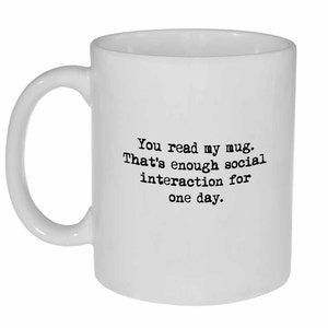 Op de afbeelding: Een witte keramische mok met zwarte tekst die "You read my mug. That's enough social interaction for one day." zegt.