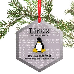 May include: A hexagonal Christmas ornament with a gray background and a penguin graphic. The ornament features code text that reads "Linux is user friendly" and "It's just VERY PICKY about who its friends are."