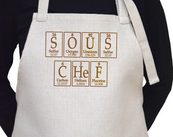 May include: A white linen apron with brown text that reads "SOUS CHEF" using the chemical symbols for the elements sulfur, oxygen, uranium, sulfur, carbon, helium, and fluorine.