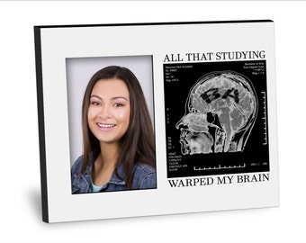 May include: A white picture frame with a black border. The frame contains a photo of a young woman on the left and a black and white image of a brain scan on the right. The brain scan has the letters "B.A." written on it. The text "ALL THAT STUDYING WARPED MY BRAIN" is printed below the images.