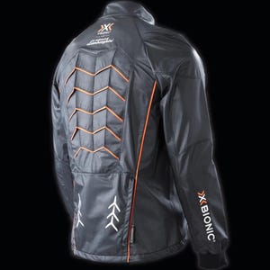 Może przedstawiać: Czarna kurtka z pomarańczowymi akcentami i pikowanym panelem tylnym. Posiada logo "X BIONIC" i "Lamborghini". Kurtka ma wysoki kołnierz i elegancki, nowoczesny design.
