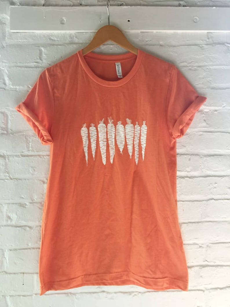 May include: A coral orange t-shirt with a white graphic of a row of carrots.
