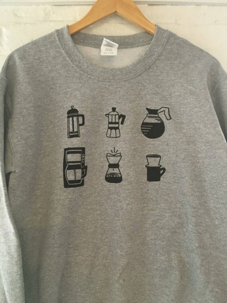 May include: Grey sweatshirt with a black graphic of different coffee brewing methods, including a French press, a percolator, a pour-over, and a drip coffee maker.