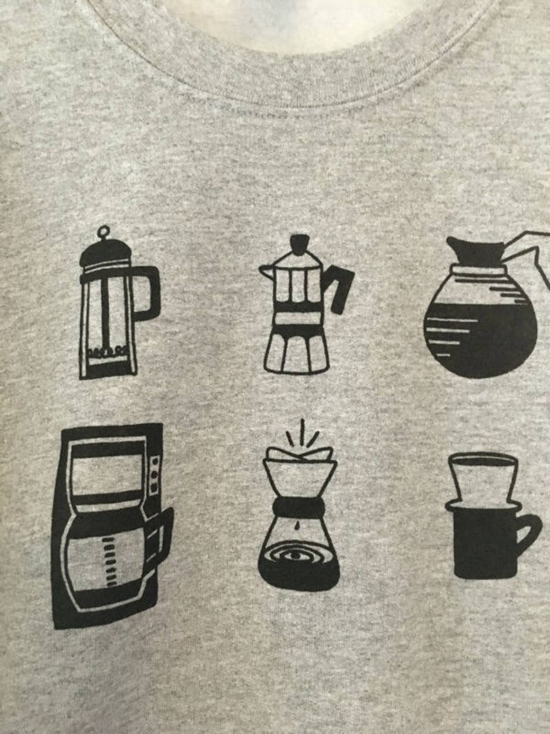 May include: A grey sweatshirt with six black illustrations of different coffee brewing methods: a French press, a Moka pot, a drip coffee maker, a pour-over coffee maker, a percolator, and a Chemex.