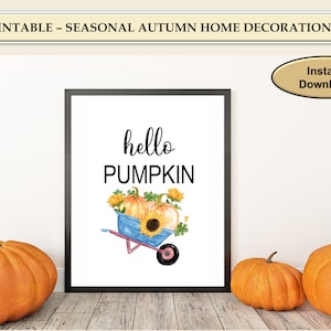 May include: A printable sign with the text "hello pumpkin" in black script font. A watercolour illustration of a wheelbarrow filled with pumpkins and sunflowers is below the text.