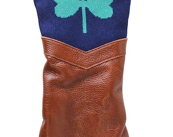 Puede incluir: Una funda para la cabeza de un palo de golf azul y marrón con un diseño de trébol verde y el número "1" bordado en el lateral.