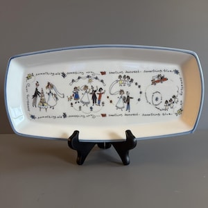 May include: A rectangular white ceramic serving tray with a light blue rim. The surface features hand-drawn illustrations of wedding scenes and the repeating text: something old, something new, something borrowed, something blue, in black ink.